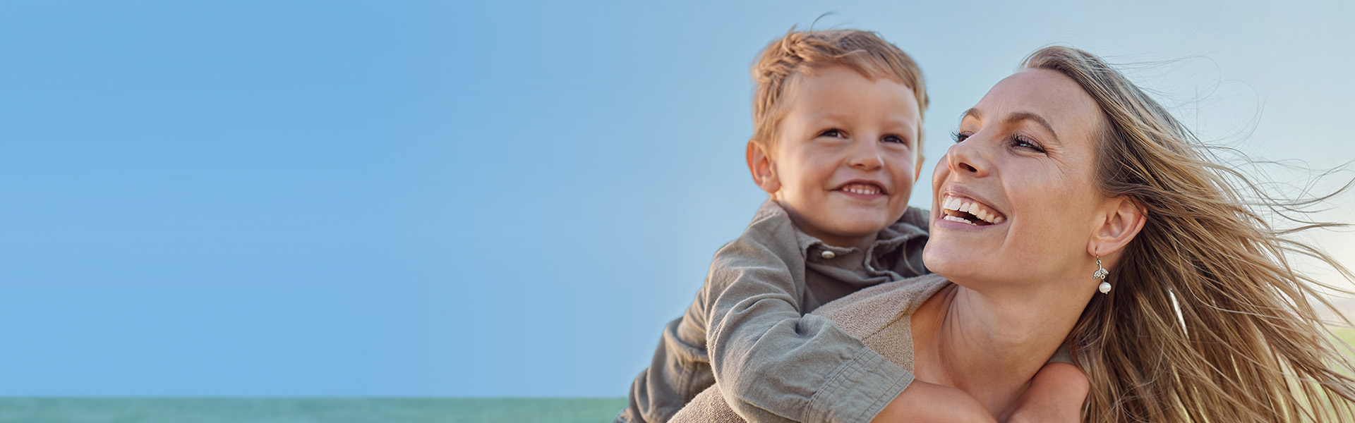 The image depicts a woman and a child on a beach, with the woman holding the child.